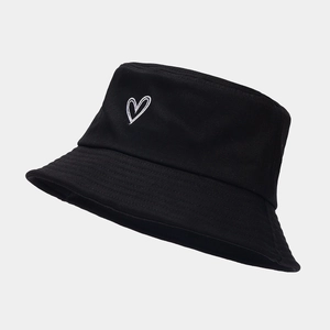 Détail de la broderie cœur blanc sur un chapeau bob en coton noir avec coutures fines