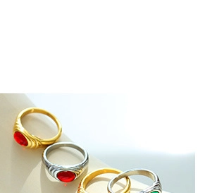 Close-up of vintage oval rings with red and green gemstones on gold and silver bands