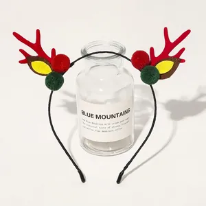 Close-up of Christmas reindeer headband with red plush antlers and colorful pom-poms