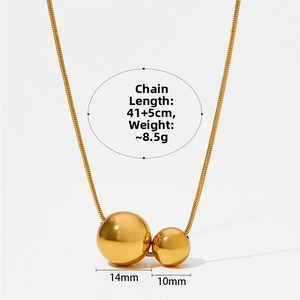 Detail of golden double bead pendant necklace showing 14mm and 10mm spheres on snake chain
