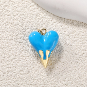 Detail of blue heart enamel pendant with gold-plated metal drip design and zircon inlay