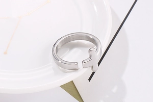 Detail shot of silver cross ring with matte finish on white ceramic edge