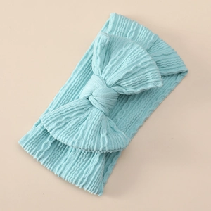 Detailed texture of light blue ribbed nylon baby headband with a large bow decoration