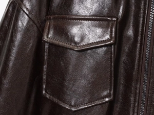 Close-up of a brown leather jacket showing pocket detail and metallic zipper texture