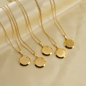 Macro shot of 18K gold plated letter pendants with round diamonds on champagne silk