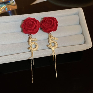 Detailed macro view of red velvet rose earrings with pearl number 5 and gold tassels