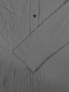 Close-up of the grey cotton linen fabric texture and black button on the men's long sleeve top