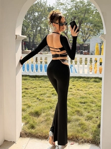 Detail of black long sleeve backless top with metal rings and hollow-out flare pants