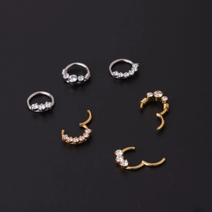 Set of gold and silver stainless steel nose rings with cubic zirconia on black background