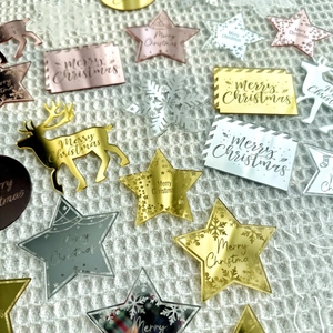 Flat lay of laser-cut acrylic Merry Christmas cake toppers in gold, silver, and rose gold