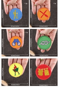 Close-up of 5cm round embroidered patches with outdoor scout themes on grey fabric