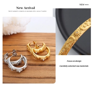 Detail view of retro gold and silver C-shaped hoop earrings with celestial star and moon patterns