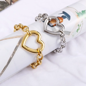 Close-up of gold and silver chunky chain bracelets with large hollow heart pendants