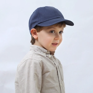 Side view of navy blue cotton baseball cap for kids on a model with clean white background