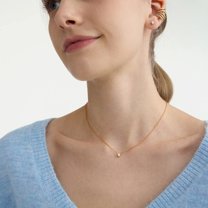 Set di collana con ciondolo a cuore dorato e orecchini di zirconi su una modella