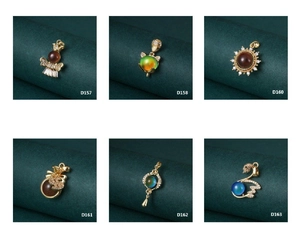 Close-up of vintage gold pendants featuring sun, swan, and lantern with color-changing stones