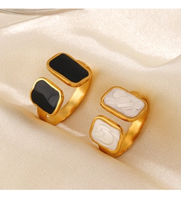 Detail of gold-plated square rings with black enamel and marble texture on silk