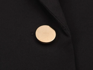 Macro detail of high-quality black woven fabric with a polished gold button fastener