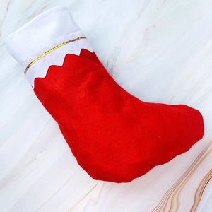 Detail of red Christmas stocking with white cuff and golden line on marble surface