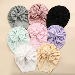 Flat lay view of eight colorful baby turban hats with large bows and eyelet fabric