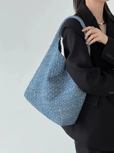 Blue denim woven tote bag shown on model featuring large capacity and stylish texture