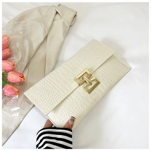 Detail of cream crocodile embossed leather clutch bag with golden geometric metal clasp