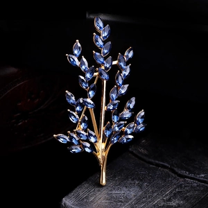 Detailed close-up of a golden branch brooch featuring elegant blue marquise-cut crystals