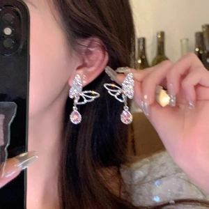 Detail view of silver butterfly earrings with pink teardrop gems worn on ear
