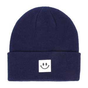 Dettaglio del cappello in maglia blu scuro per neonati con patch sorriso carino