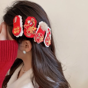 Detail of red New Year hair clips with zodiac embroidery and fluffy pompom accents