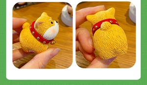 Detail view of a cute resin Shiba Inu figurine with red collar and golden bell