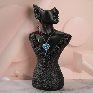 Detail view of a black resin mannequin bust showcasing blue heart jewelry on a marble base