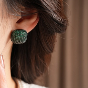Close-up of model wearing dark green zircon square stud earrings with black metal base