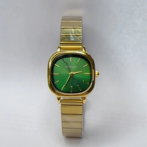 Detailed macro of a women's square gold watch with a green dial and elastic metal band