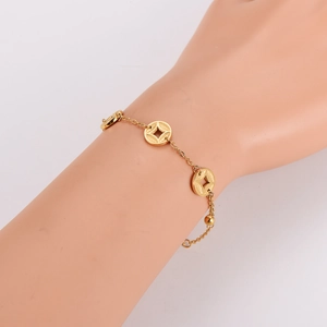 Close-up of a gold-finish ancient coin bracelet on a model's wrist with minimalist design