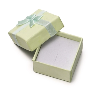 Close-up of light green jewelry gift box with a blue silk bow and white inner padding