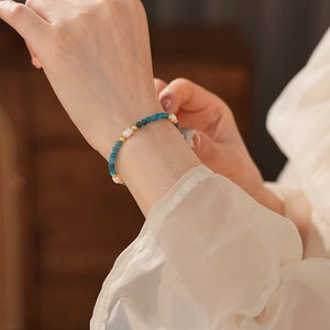 Close-up of a beaded bracelet with blue stones and freshwater pearls on a wrist