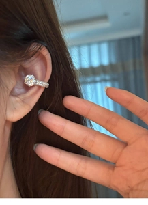 Close-up of a silver zircon ear cuff featuring a large round diamond on a model's ear