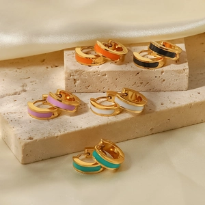 Detail of five colorful enamel hoop earrings in gold finish on a luxury stone texture