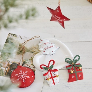 Christmas metal hanging ornaments featuring red stars and trees on white tray
