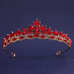 Elegant gold bridal crown with red rhinestones and crystals on a dark background