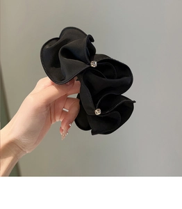 Detail of a black pleated satin scrunchie featuring elegant sparkling rhinestone accents