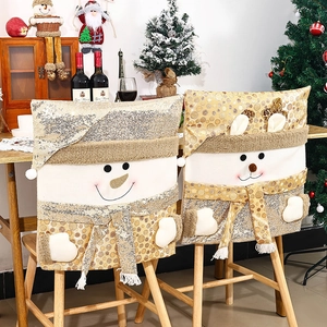 Festive gold sequin Christmas chair covers with snowman and reindeer designs in warm home setting