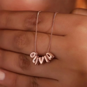 Detail of custom 3D bubble letter necklace spelling OLIVIA in polished rose gold finish