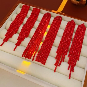 Macro view of red rhinestone tassel earrings set in a beige velvet jewelry display box