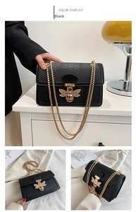 Detail of black crocodile embossed leather bag with golden bee buckle and chain strap