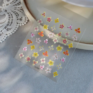 Floral embossed nail art stickers with gold details on a white lace and ceramic tray