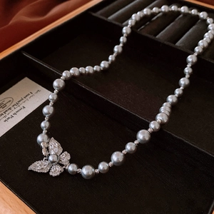 Vue détaillée du collier de perles gris argenté avec pendentif papillon en zircon en boîte