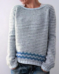 Detail of grey and white striped knit sweater featuring blue wave patterns on the hemline