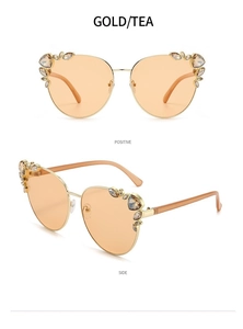 Close-up of cat-eye sunglasses with gold frame and tea-colored rhinestone details